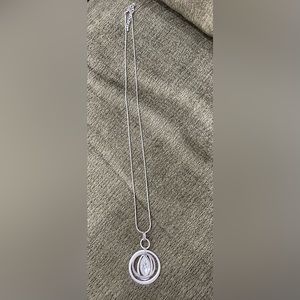 Long silver necklace with multi-loop pendant and clear faceted stone.